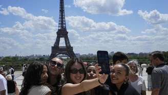 Turistas posam para uma selfie com a Torre Eiffel ao fundo em 6 de julho de 2023, em Paris (imagem ilustrativa).
