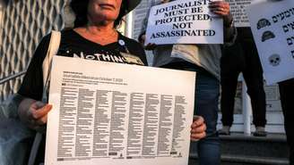 Uma mulher segura um cartaz com os nomes dos jornalistas mortos em conflitos nos territórios palestinos, no Líbano e em Israel desde 7 de outubro de 2023
