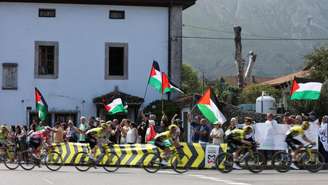 Os ciclistas passam por manifestantes com bandeiras da Palestina durante a etapa 13 da "Vuelta a Espana", em Cabezon de la Sal a L'angliru, Cantábria, Espanha em 5 de setembro de 2025.