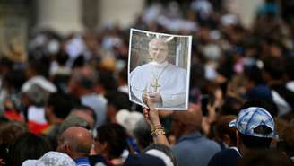 Fieis reunidos na Praça de São Pedro seguram uma imagem do Papa Leão XIV para lhe desejar um feliz aniversário, durante sua oração do Angelus, no Vaticano, em 14 de setembro de 2025.