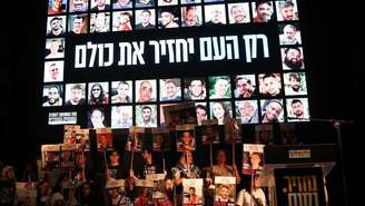 Pessoas seguram fotos de reféns israelenses enquanto se reúnem na "Praça dos Reféns" em Tel Aviv, para comemorar o acordo assinado entre Israel e o Hamas para uma troca de reféns por prisioneiros, baseada em um plano de 20 pontos proposto pelo presidente norte-americano Donald Trump, em 11 de outubro de 2025.