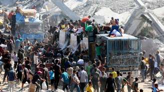 Palestinos recolhem alimentos em caminhões que entraram em Gaza, em Khan Younès, no sul da Faixa de Gaza, em 12 de outubro de 2025
