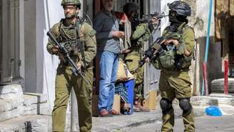 Soldados do exército israelense marcham por uma rua durante uma operação militar em um bairro de Nablus, na Cisjordânia ocupada, em 5 de outubro de 2025.
