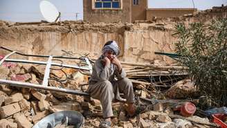 Um sobrevivente do terremoto no Afeganistão senta sobre os escombros de uma casa destruída em uma vila de Tashqurghan, no distrito de Khulm, província de Samangan