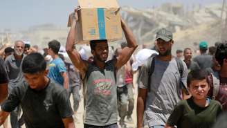 Homem palestino carrega caixa de comida obtida no ponto de passagem de Zikim, no norte da Faixa de Gaza, em 1º de agosto de 2025.