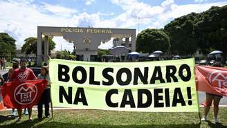 Membros do Movimento dos Trabalhadores Sem-Teto (MTST) exibem faixa diante da superintendência da Polícia Federal, em Brasília, onde o ex-presidente Jair Bolsonaro está preso preventivamente. Brasília, 22 de novembro de 2025.