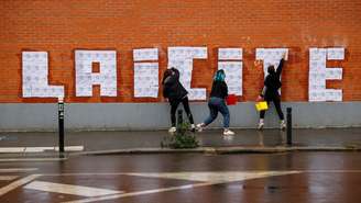 Foto de ilustração. Três ativistas feministas criam uma colagem em uma parede em Montreuil, em 20 de outubro de 2020, durante um evento em homenagem à equipe do Charlie Hebdo.