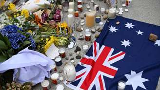 Bandeira australiana é colocada perto de flores depositadas em homenagem às vítimas do ataque antissemita que deixou 15 mortos na praia Bondi Beach, em Sydney. Imagem de 16 de dezembro de 2025.
