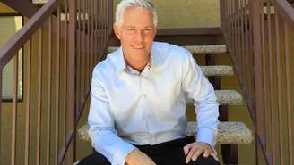 Paul sentado em uma cadeira olhando para a câmera