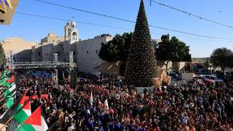 Cenenas de fiéis se reúnem ao lado da árvore de Natal na Praça da Manjedoura, na véspera de Natal, na Cidade Velha de Belém, na Cisjordânia ocupada por Israel, em 24 de dezembro de 2025.