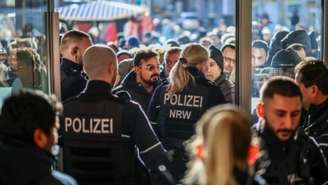 Policiais tentam conter clientes preocupados em frente a uma agência do banco Sparkasse em Gelsenkirchen, oeste da Alemanha, em 30 de dezembro de 2025, após o assalto à instituição.