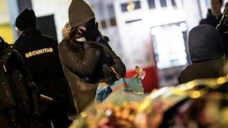 Mulher diante de flores e velas colocadas perto do local onde um incêndio devastou um bar lotado durante as comemorações de Ano-Novo na estação de esqui alpina de Crans-Montana, na Suíça.