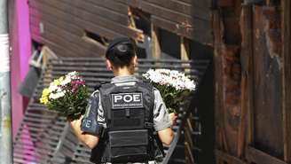 Uma policial de Santa Maria, no Rio Grande do Sul, leva flores para a frente da boate Kiss em homenagem às vítimas do incêndio no dia seguinte à tragédia, em 28 de janeiro de 2013.