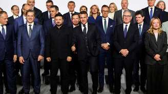 O presidente francês, Emmanuel Macron, gesticula enquanto o primeiro-ministro polonês, Donald Tusk, o primeiro-ministro esloveno, Robert Golob, o presidente ucraniano, Volodymyr Zelensky, o primeiro-ministro britânico, Keir Starmer e a primeira-ministra italiana, Giorgia Meloni, reagem ao chegarem para posar para uma foto à margem da chamada cúpula da "coalizão de voluntários", no Palácio do Eliseu, em Paris, França, em 6 de janeiro de 2026.