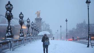 Uma pessoa se protege da neve na Ponte Alexandre III, em Paris, enquanto o clima de inverno com neve e baixas temperaturas atinge parte da França, 7 de janeiro de 2026.