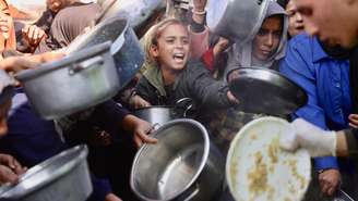 Palestinos deslocados se reúnem para receber alimentos doados em uma cozinha beneficente em Khan Yunis, no sul da Faixa de Gaza, em 17 de dezembro de 2025. (Foto ilustrativa)