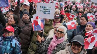 Manifestante exibe cartaz com a mensagem "tirem as as mãos da Groenlândia", em protesto diante da prefeitura de Copenhague, na Dinamarca, em 17 de janeiro de 2026.