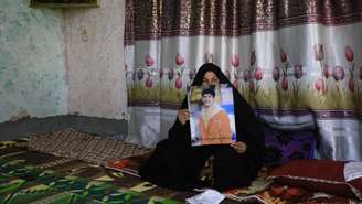 Uma mãe iraquiana mostra uma foto de seu filho, com quem perdeu contato depois que ele partiu para a Rússia para se juntar às forças armadas, ao sul de Bagdá, em 10 de setembro de 2025.