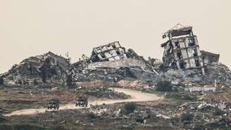 Veículos militares israelenses passam por locais destruídos em Gaza, vistos do lado israelense da fronteira entre Israel e Gaza, no sul de Israel, em 21 de janeiro de 2026.