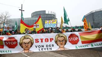 Agricultores seguram uma faixa com caricaturas da presidente da Comissão Europeia, Ursula von der Leyen, em frente ao Parlamento Europeu, durante sessão de votação do acordo UE-Mercosul, em Estrasburgo, em 20 de janeiro de 2026.