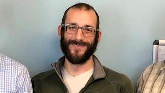 Alex Pretti é visto sorrindo com um suéter verde.