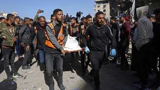 Equipes de resgate carregam o corpo de uma vítima em meio aos escombros da delegacia de polícia de Sheikh Radwan, na Cidade de Gaza, em 31 de janeiro de 2026, após um ataque aéreo israelense. Em Gaza, em 31 de janeiro.