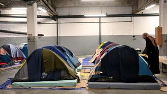 Mulher em um estacionamento transformado pela associação humanitária francesa Utopia 56 em um abrigo noturno temporário com tendas, próximo ao Arco do Triunfo, em Paris, em 1º de março de 2023.