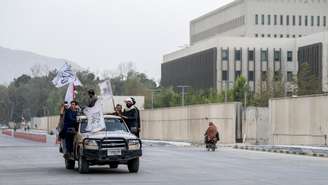 Forças de segurança talibãs desfilam com bandeiras diante da antiga embaixada dos EUA, em Cabul, em 15 de agosto de 2025, no quarto aniversário da volta do grupo ao poder.