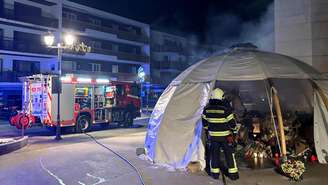 Bombeiros controlam o fogo neste dia 8 de fevereiro no memorial em frente ao bar “Le Constellation”, em homenagem às vítimas do incêndio fatal que devastou o bar na véspera de Ano-Novo em Crans-Montana.
