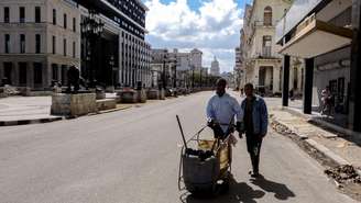 Agentes de limpeza empurram um carrinho enquanto caminham por uma rua deserta de Havana, em 8 de fevereiro de 2026.