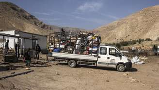 Homens ajudam uma família beduína a colocar seus objetos em um caminhão ao deixarem sua casa após meses de conflitos com colonos israelenses próximo a Jericó, na Cisjordânia, em 8 de janeiro de 2026.