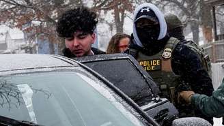 Um homem é conduzido para um carro após ser detido por agentes do Serviço de Imigração (ICE) durante uma operação de imigração em Minneapolis, Minnesota, EUA, em 18 de janeiro de 2026.