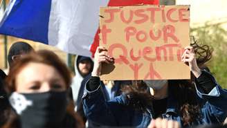 Manifestante exibe cartaz com os dizeres "Justiça para Quentin", em ato realizado em Montpellier, no sul da França, neste domingo, 15 de fevereiro de 2026.