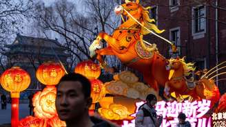 Pessoas se reúnem perto de uma instalação luminosa representando o Cavalo de Fogo com a torre Zhengyang Gate ao fundo, na véspera do Ano Novo Lunar, em Pequim, China, em 13 de fevereiro de 2026.