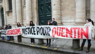 Manifestantes exibem uma faixa em homenagem ao jovem Quentin Deranque neste domingo, 15 de fevereiro de 2026, um dia após a morte do militante de extrema direita em Lyon.