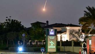 Um ciclista observa um projétil cair sobre Dubai em 28 de fevereiro de 2026. As explosões ocorreram na sequência de ataques generalizados do Irã no Golfo, em retaliação aos ataques dos EUA e de Israel contra o Irã.