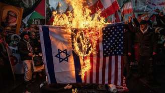 Apoiadores do governo iraniano queimam bandeiras americanas e israelenses durante um protesto pró-governo iraniano realizado em frente ao consulado iraniano em Istambul, Turquia, em 18 de janeiro de 2026.