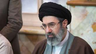 Mojtaba Khamenei, com um turbante preto e uma túnica marrom, desvia o olhar da câmera.