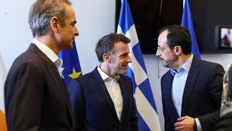 O presidente francês Emmanuel Macron (C) se reúne com o presidente do Chipre, Nikos Christodoulides, e o primeiro-ministro grego, Kyriakos Mitsotakis, durante uma visita para discutir segurança regional, em Pafos, Chipre, em 9 de março de 2026. A França enviou navios de guerra para o Mediterrâneo para "missão estritamente defensiva", no âmbito da guerra entre EUA e Israel contra o Irã.