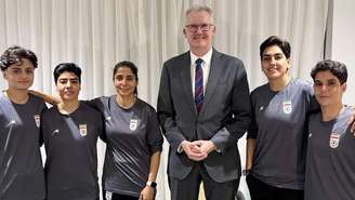 O ministro do Interior da Austrália, Tony Burke, ao lado das cinco jogadoras iranianas que obtiveram asilo no país. À esquerda do ministro estão Fatemeh Pasandideh, Mona Hamoudi e Atefeh Ramezanizadeh. À direita estão Zahra Ghanbari e Zahra Sarbali.