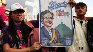 Eleitora colombiana segura cartaz com imagem do candidato Iván Cepeda, do Pactro Histórico, vencedor das eleições legislativas no domingo, 08/03/2026.