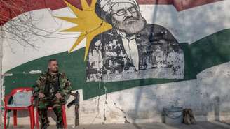 Um combatente curdo, membro da Organização de Luta do Curdistão Iraniano (Sazmani Khabat), guarda o portão de sua base perto de Erbil, na região autônoma curda do norte do Iraque, em 9 de março de 2026. No contexto de uma coalizão internacional antijihadista liderada pelos Estados Unidos, militares de vários países, incluindo a França e a Itália, estão treinando membros das forças de segurança curdas no Curdistão iraquiano.