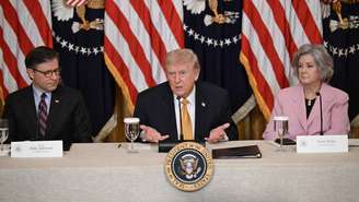 O presidente dos EUA, Donald Trump (C), acompanhado pelo presidente da Câmara dos Representantes, Mike Johnson, e pela chefe de gabinete da Casa Branca, Susie Wiles, durante um almoço com membros do Conselho do Kennedy Center no Salão Leste da Casa Branca, em 16 de março de 2026, em Washington, DC.