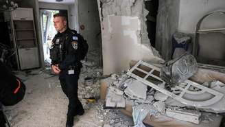 Policiais israelenses inspecionam um prédio danificado por um ataque de projétil iraniano em Rishon LeZion, no centro de Israel, em 16 de março de 2026.