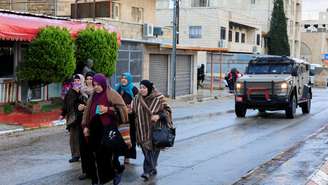 Palestinos caminham em direção a um posto de controle israelense para chegar ao complexo de Al-Aqsa em Belém, na Cisjordânia ocupada por Israel, em 27 de fevereiro de 2026.