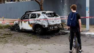 Um jovem ciclista observa os danos causados por mísseis iranianos em Petah Tikva, Israel, em 18 de março de 2026.