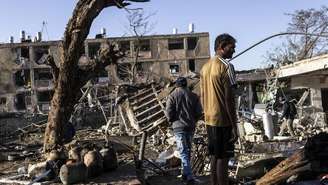 Pessoas observam local de ataque de míssil iraniano em Dinoma, Israel, em 22 de março de 2026.