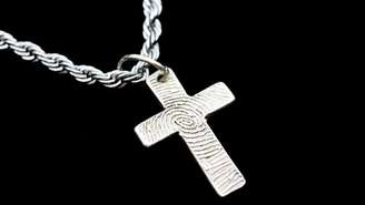 Cruz de prata presa a uma corrente prateada sobre fundo preto