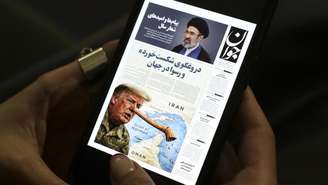 Uma mulher iraniana lê uma cópia digital do jornal Javan em seu celular em Teerã, em 25 de março de 2026. Jornais iranianos ridicularizaram, em 25 de março, o que chamaram de "mentiras" de Donald Trump sobre as negociações diplomáticas em andamento para pôr fim à guerra, publicando charges do presidente americano estilizado como Pinóquio.