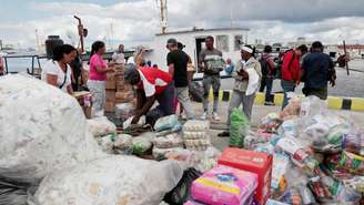 Ativistas da flotilha Nuestra América e autoridades cubanas descarregam ajuda humanitária do navio "Granma 2.0" no porto de Havana, em 24 de março de 2026.